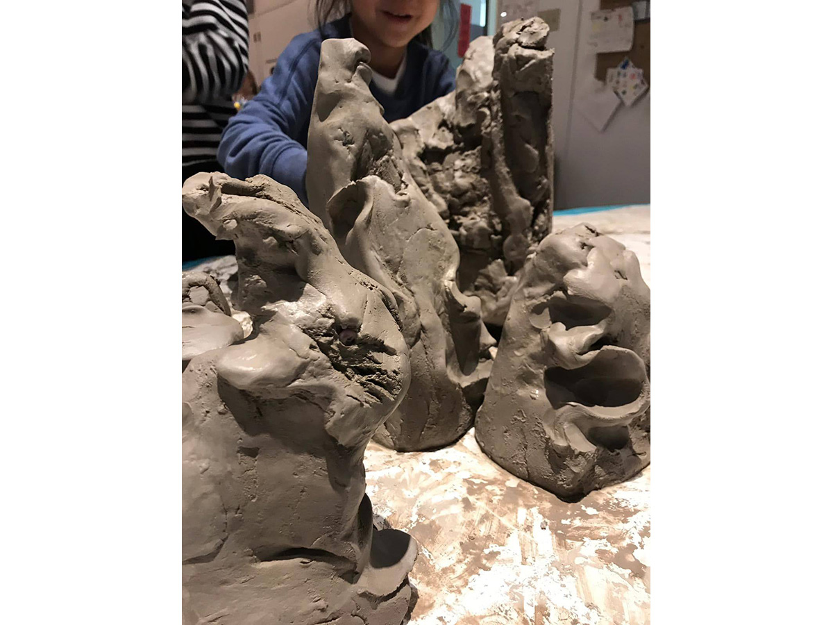 Large lumps of wet clay with a child in the background.