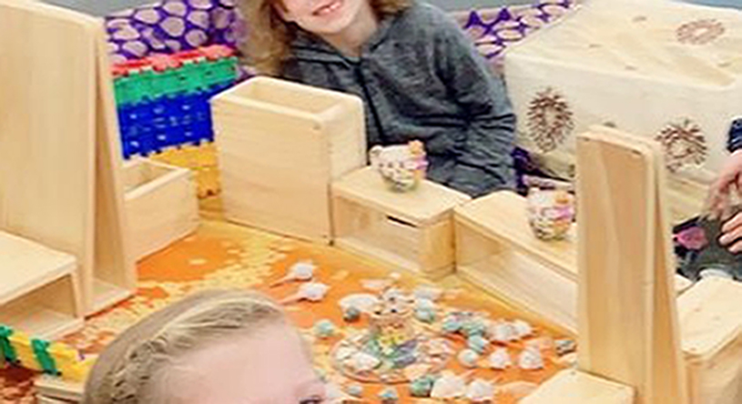 Kids displaying their creations made with wooden boxes and loose parts